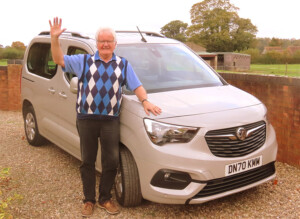 John Batchelor, experienced Cotswolds tour guide, standing beside a private tour vehicle and welcoming guests to a bespoke Cotswolds tour